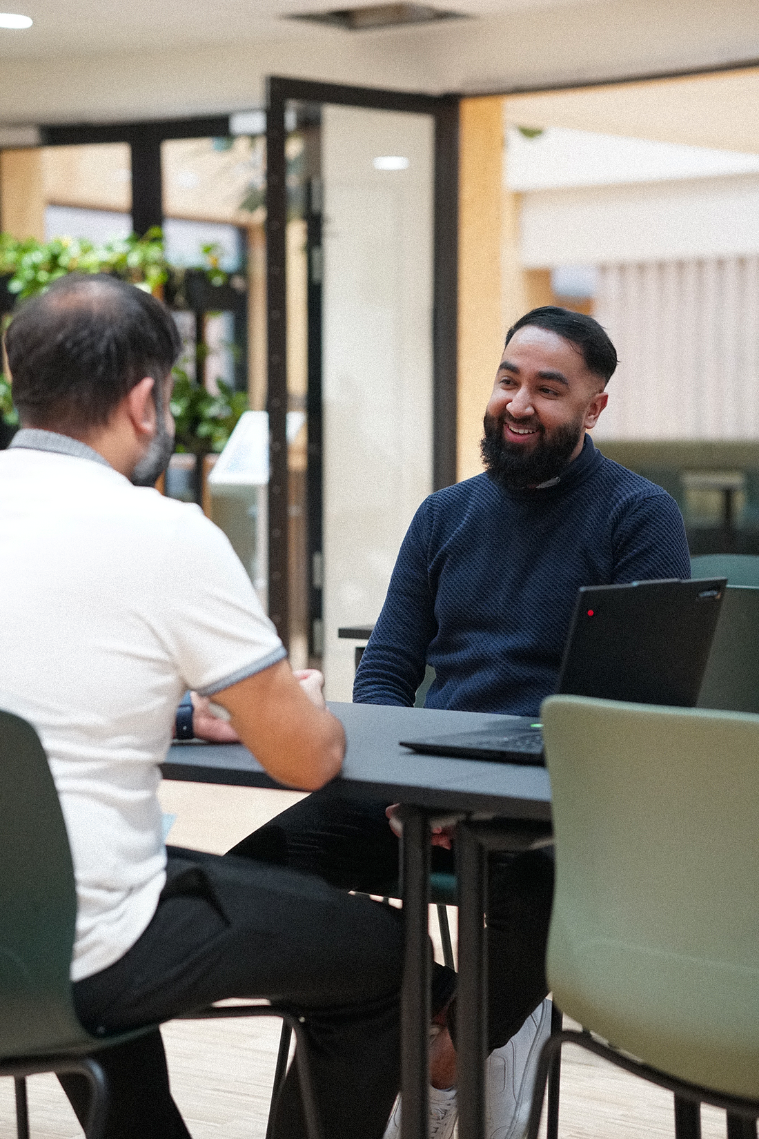 Hamza sidder ved et bord og taler med kollega